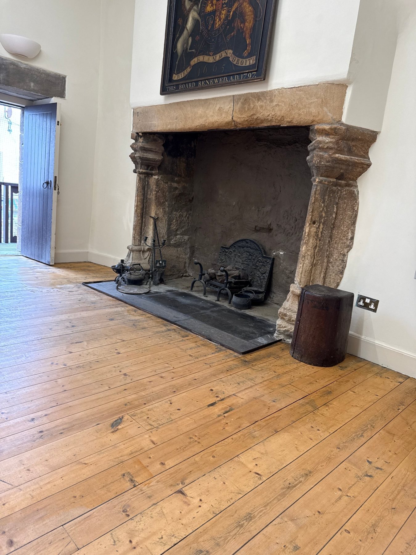 The great stone fireplace in the Great Hall, with the royal arms board above